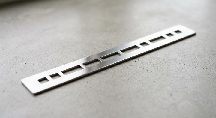 Close-up of a high-precision metal strip with geometric cutouts representing high-volume stamping