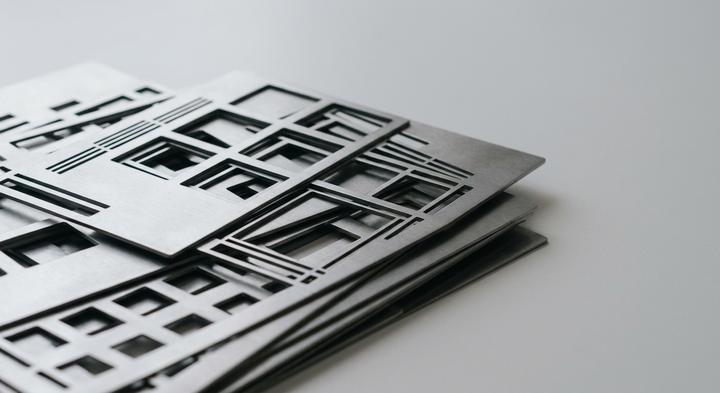 Abstract matte steel sheets with precise geometric cutouts under soft studio side-lighting.