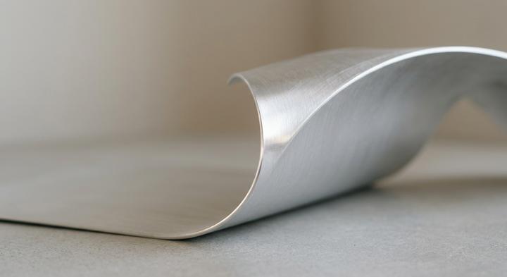 Minimalist macro shot of a clean, bent aluminum sheet showcasing precise manufacturing tolerances